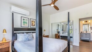 Een moderne slaapkamer met een groot bed, een plafondventilator en uitzicht op de badkamer.
