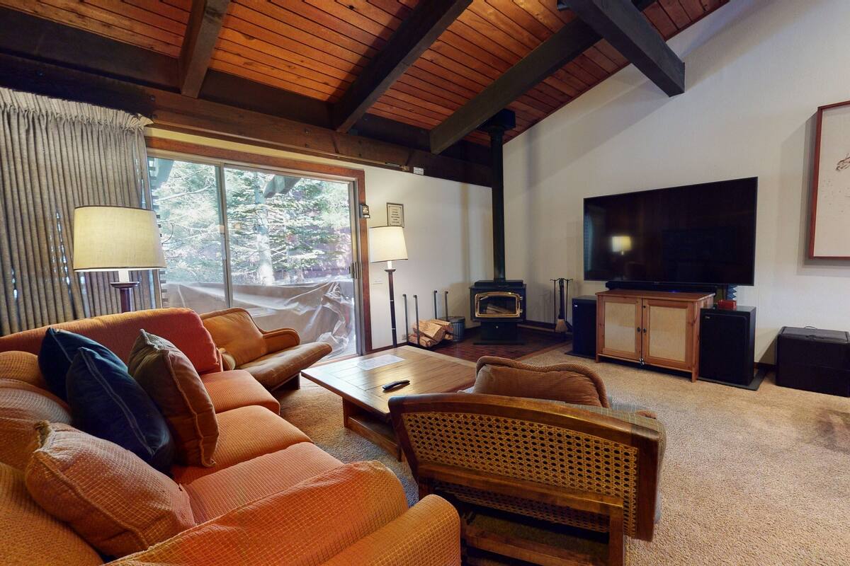 A cozy living room with a sofa, a coffee table, a television, and a fireplace.