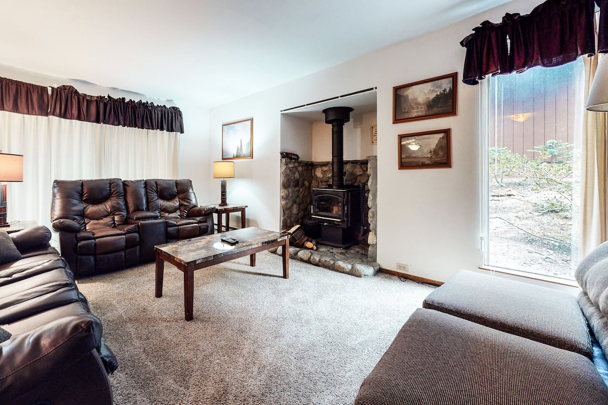 A cozy living room with a fireplace, leather sofas, and a stone wall.
