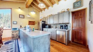 A kitchen with a central island, stainless steel appliances, wooden ceiling beams, and a rustic aesthetic. - Rainbow Villas 1 Charming Boutique complex, Dual Master Suites, Forest Mountain Views by RedAwning (Mammoth Lakes)
