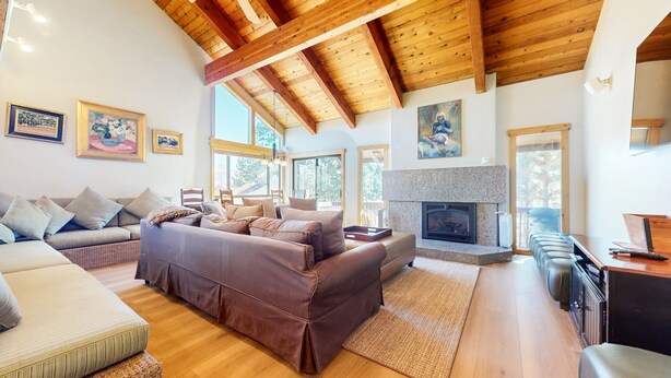 A spacious living room with a brown leather sofa, a wooden ceiling, and a fireplace. - Val DIsere 10 5-Star Luxury with Game room and Gorgeous Mountain Views, Walk to The Village. by RedAwning (Mammoth Lakes)