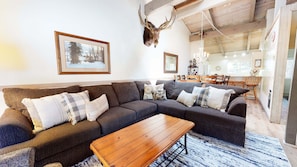 A cozy living room with a sectional sofa, a wooden coffee table, and a mounted deer head.