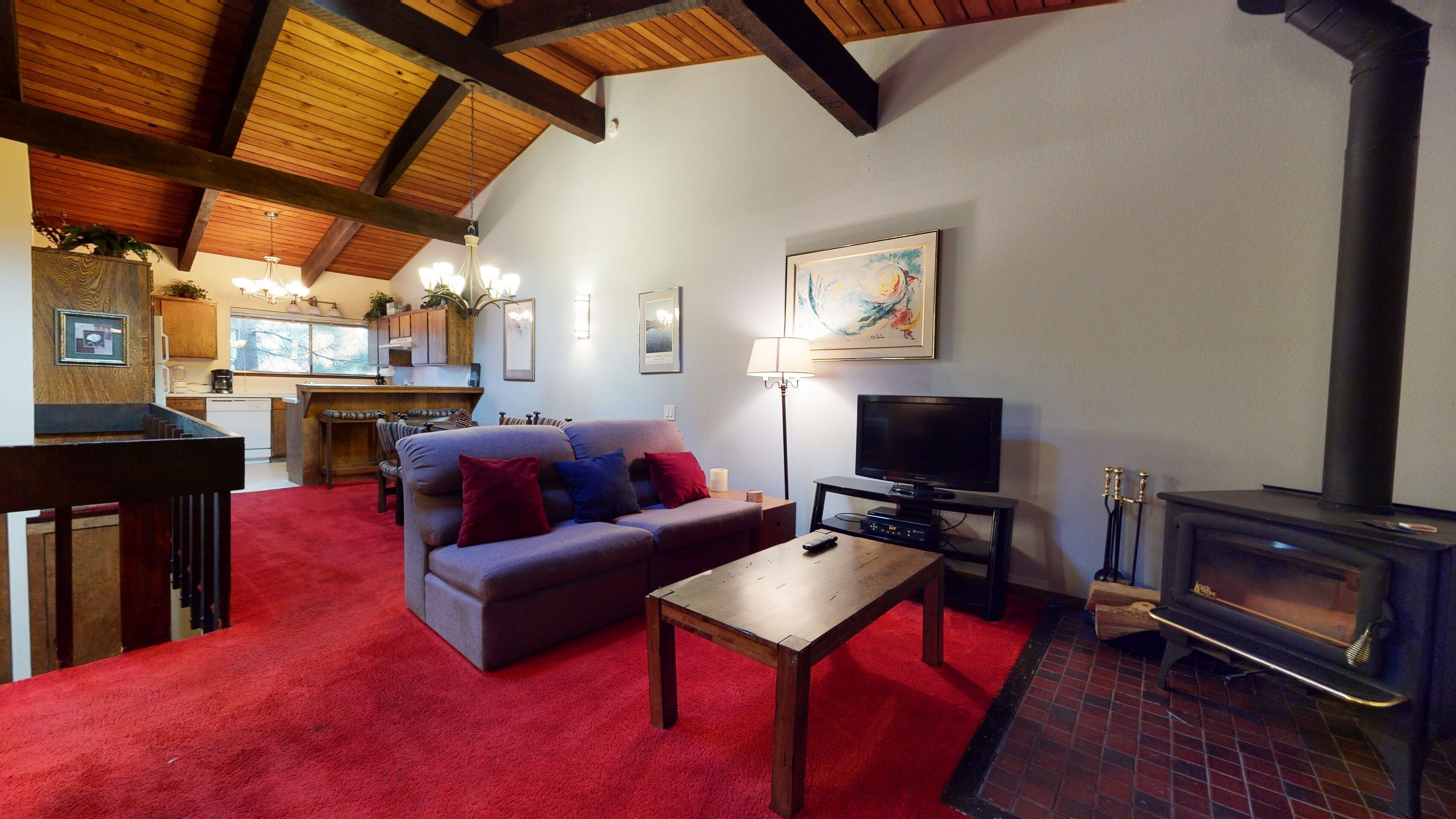 Una sala de estar acogedora con sofá, televisión, chimenea y una cocina al fondo.
