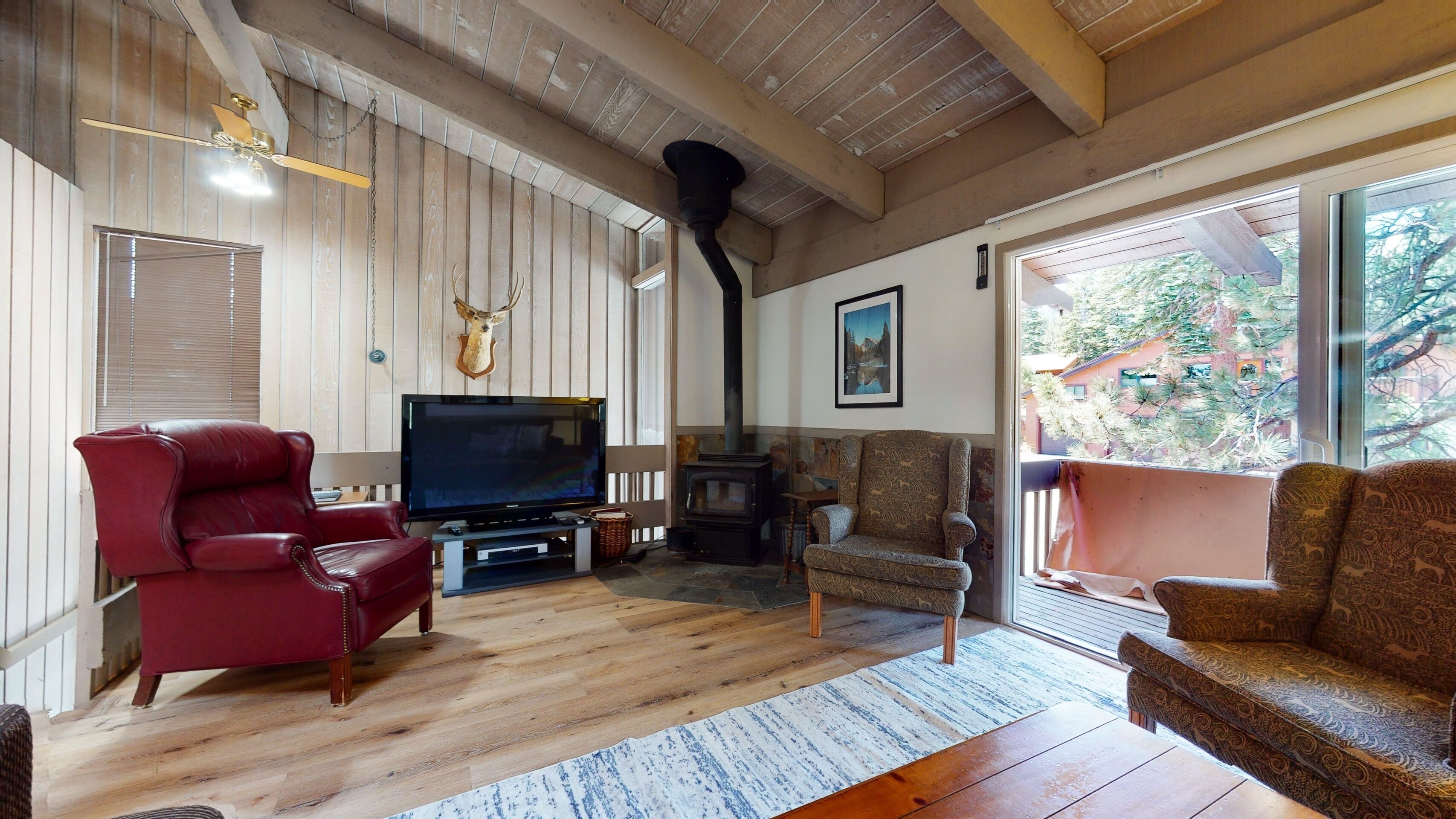 A cozy living room with a fireplace, a television, and a red leather chair.