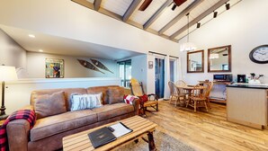Ein gemütliches Wohnzimmer mit einer braunen Ledersofa, einem Holztisch und einem Essbereich mit Tisch und Stühlen.