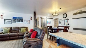 A living room with a sofa, a chair, a dining table, and a kitchen area with a sink and cabinets.