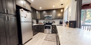 A modern kitchen with dark wood cabinets, stainless steel appliances, and a marble countertop.