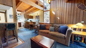 Ein gemütliches Wohnzimmer mit einem Holzsofa, einem Couchtisch und einem Essbereich mit Holztisch und Stühlen.
