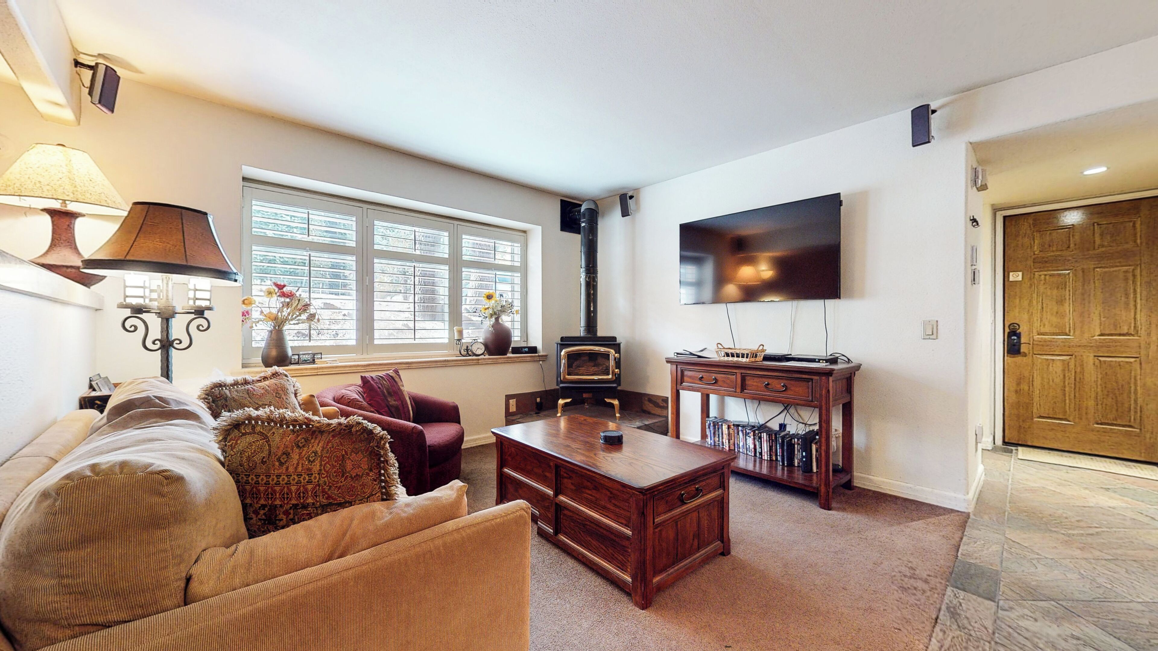 A living room with a sofa, armchair, coffee table, fireplace, TV, and a bookshelf.