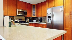 Una cucina con mobili in legno, elettrodomestici in acciaio inossidabile, un piano di lavoro in granito e forno integrato.