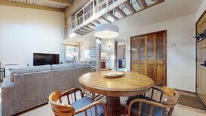 A spacious living area with a high ceiling, a round wooden table, and a grey sofa. - Pet Friendly, Walk To The Village. Pool On-Site & Great Complex Amenities (Mammoth Lakes)