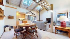 A spacious living area with a round wooden table, a grey sofa, and a television. - Pet Friendly, Walk To The Village. Pool On-Site & Great Complex Amenities (Mammoth Lakes)