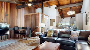 A spacious living area with a leather sofa, wooden flooring, and a ceiling fan.