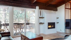 Una sala de estar con chimenea, muebles de madera y vistas al exterior.