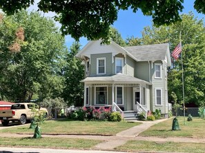 A two-story house with a porch, a flag, and a truck parked in front.
