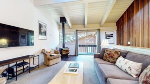 A cozy living room with a fireplace, a sofa, a coffee table, and a TV.