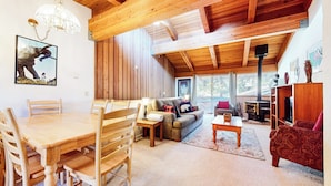 Ein gemütliches Wohnzimmer mit Holzmöbeln, einem Kamin und großen Fenstern.