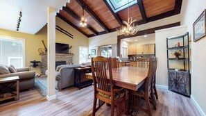 A spacious living area with a fireplace, a dining table, and a kitchen in the background.