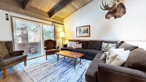 A cozy living room with a large window, a mounted moose head, a sofa, a chair, and a coffee table. - Pet-Friendly Large Home, Near The Village, Pool & Hot Tub On-site (Mammoth Lakes)