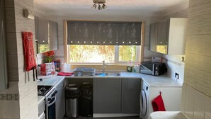 A compact kitchen with a built-in oven, a sink, a washing machine, and a microwave. - 3bed House - Family Friendly - Close To Lochness (Inverness)