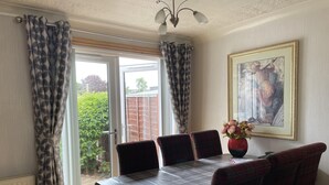 A dining area with a table set for four, a vase of flowers, and a framed artwork on the wall. - 3bed House - Family Friendly - Close To Lochness (Inverness)