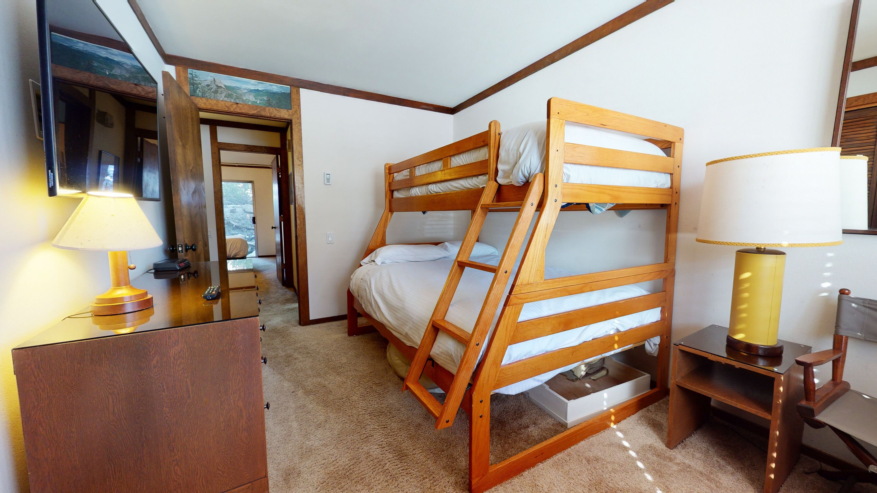 A bunk bed room with a desk, lamp, and a mirror.