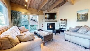 A cozy living room with a fireplace, two sofas, a coffee table, and a TV mounted on the wall.