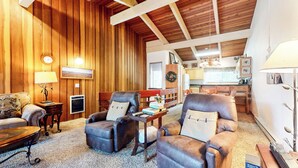 A cozy living room with leather armchairs, a wooden ceiling, and a kitchen in the background. - Family Favorite Home. Private Balcony & Near The Village, Pool On-site (Mammoth Lakes)