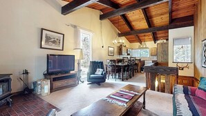 Un salon confortable avec une cheminée, un téléviseur, un coin repas et une cuisine.