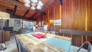 Un intérieur en bois comprenant une table à manger, des chaises, une cheminée et une vue par une fenêtre.