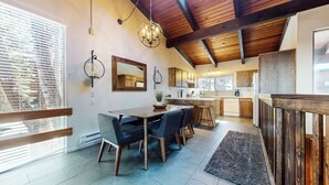 Una cocina moderna con armarios de madera, una isla central y un comedor con mesa y sillas.
