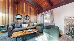 Una sala de estar acogedora con techo de madera, un sofá, una mesa de centro y una chimenea de ladrillo.