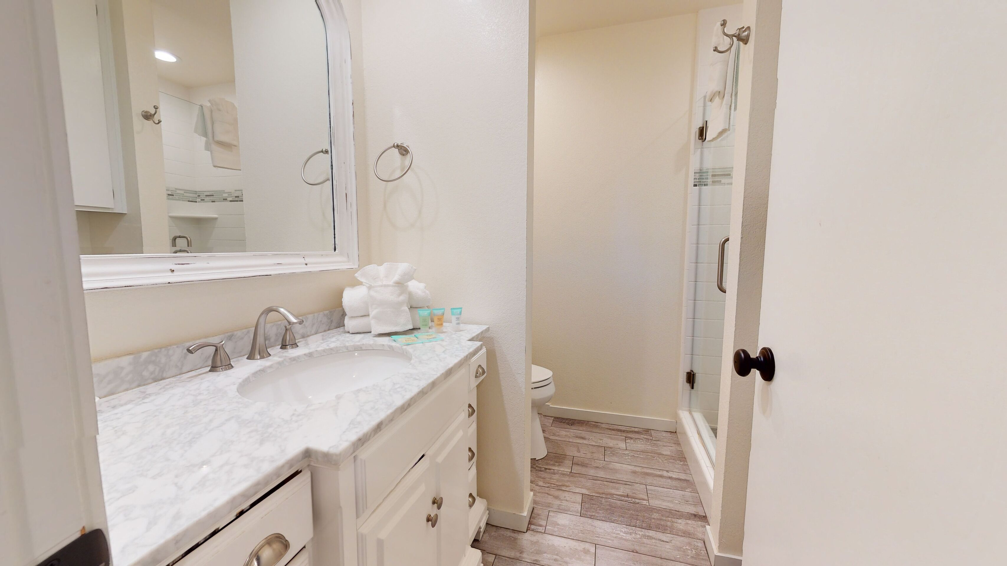 Une salle de bain avec un lavabo en marbre, un miroir, des toilettes et un espace douche.