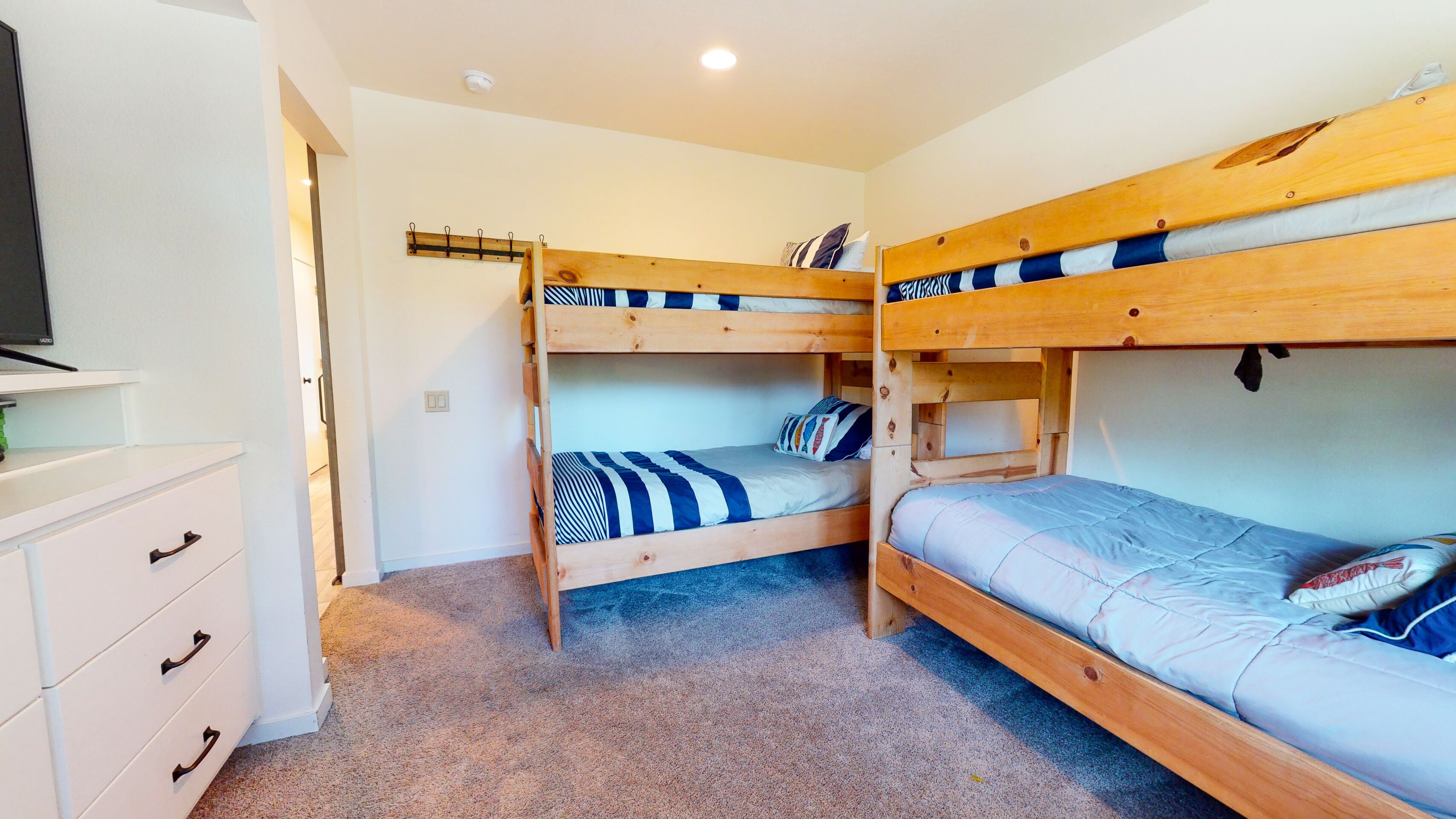 A room with bunk beds, a TV, and a white dresser.