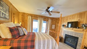 A wooden room with a bed, a fireplace, a television, and a ceiling fan. - Family and Pet Friendly Mtn Top Cabin, Double Porch, High-Speed WiFi/SmartTVs (Ferguson)