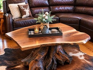A wooden coffee table with a natural wood base, a tray with candles, and a vase with flowers. - The Great Dane: Family and Pet Friendly Mtn Top Cabin, Double Porch, High-Speed (Ferguson)