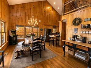 A wooden interior with a dining area, a coffee station, and a view through the windows. - The Great Dane: Family and Pet Friendly Mtn Top Cabin, Double Porch, High-Speed (Ferguson)