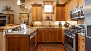 Una cocina con armarios de madera, un refrigerador de acero inoxidable, un microondas, una estufa y un lavamanos.