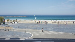 Une promenade en bord de mer offrant une vue sur l’océan, une tour de surveillance des sauveteurs et un passage piéton.