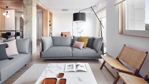Un salon moderne avec un canapé gris, un fauteuil en osier et une table basse sur laquelle sont posés des magazines.