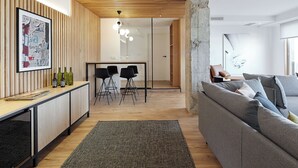 Un espace de vie moderne agrémenté d’un mur d’accent en bois, d’un coin repas avec des tabourets de bar et d’un canapé gris.
