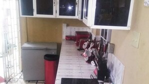A compact kitchen with a tiled floor, a refrigerator, a sink, and cabinets above the countertop. - Immaculate 2-bed Apartment in Spanish Town (Spanish Town)