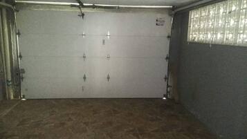 A garage with a closed door, a tiled floor, and a window on the right side.