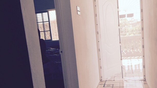 A hallway with a tiled floor and a door leading to a balcony. - Immaculate 2-bed Apartment in Spanish Town (Spanish Town)