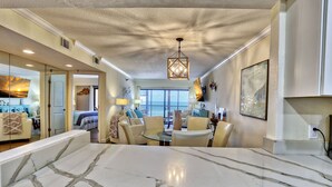 A spacious living area with a marble island, a chandelier, and a balcony with a view. - Villa Madeira 406 Gorgeous, Beach Front, Top Location! (Madeira Beach)