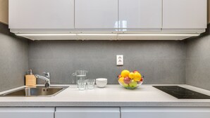 A modern kitchen with a stainless steel sink, a built-in stove, and a bowl of fruit on the countertop. - Luxurious sunlit suite in a prime location with a private city-view balcony, A/C (Budapest)