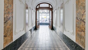 A hallway with a marble floor, white walls, and a large arched doorway at the end. - Luxurious sunlit suite in a prime location with a private city-view balcony, A/C (Budapest)