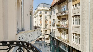 A narrow street with buildings on either side, featuring balconies with plants and a wrought iron railing. - Luxurious sunlit suite in a prime location with a private city-view balcony, A/C (Budapest)