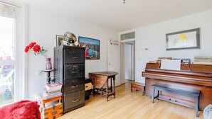 Ein Zimmer mit einem Klavier, einem Aktenschrank, einem kleinen Tisch und einem Globus auf dem Schrank.