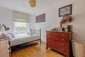 Un dormitorio con cama, cómoda, ventana y obras de arte.